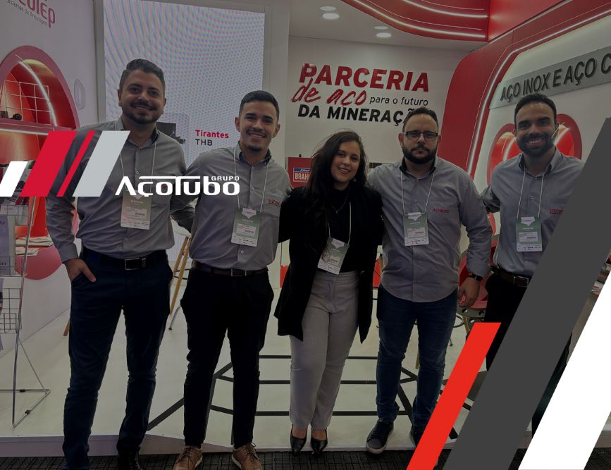 Cinco colaboradores do Grupo Açotubo lado a lado em frente ao estande da empresa na Exposibram 2025